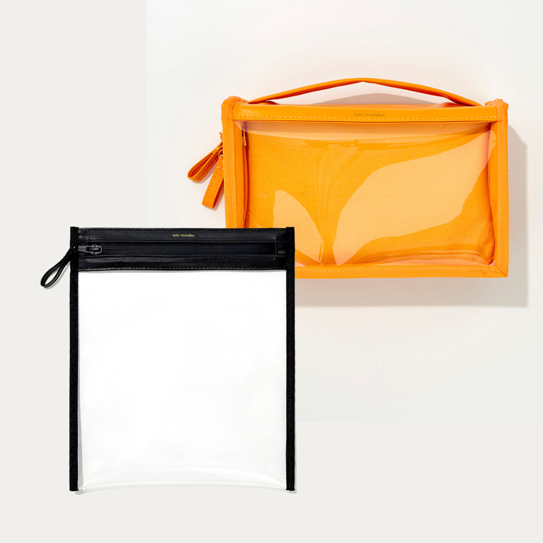 Product photograph by take mooday featuring two transparent travel pouches on a white background one vibrant orange with a top handle and clear front panel and a second smaller clear rectangular pouch with black trim and a black zipper pull